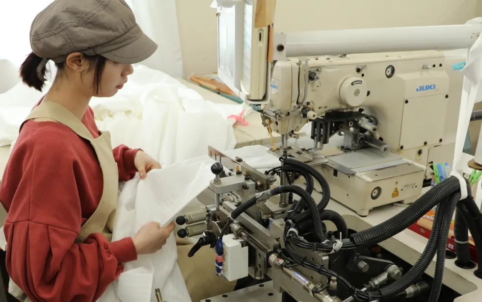 作業帽をかぶった若い作業員が、先輩スタッフとともに工具を使いながら作業手順を学んでいる様子。